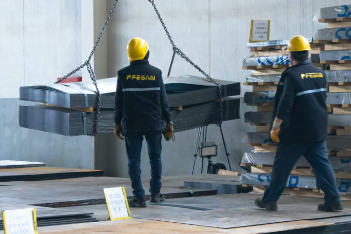 Two people in yellow hard hats supervising a delivery of Hardox® wear plate