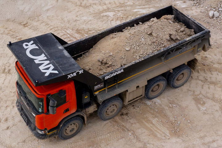 A dump truck carrying rocks in an open-pit mine, with XMOR truck body in Hardox® wear plate