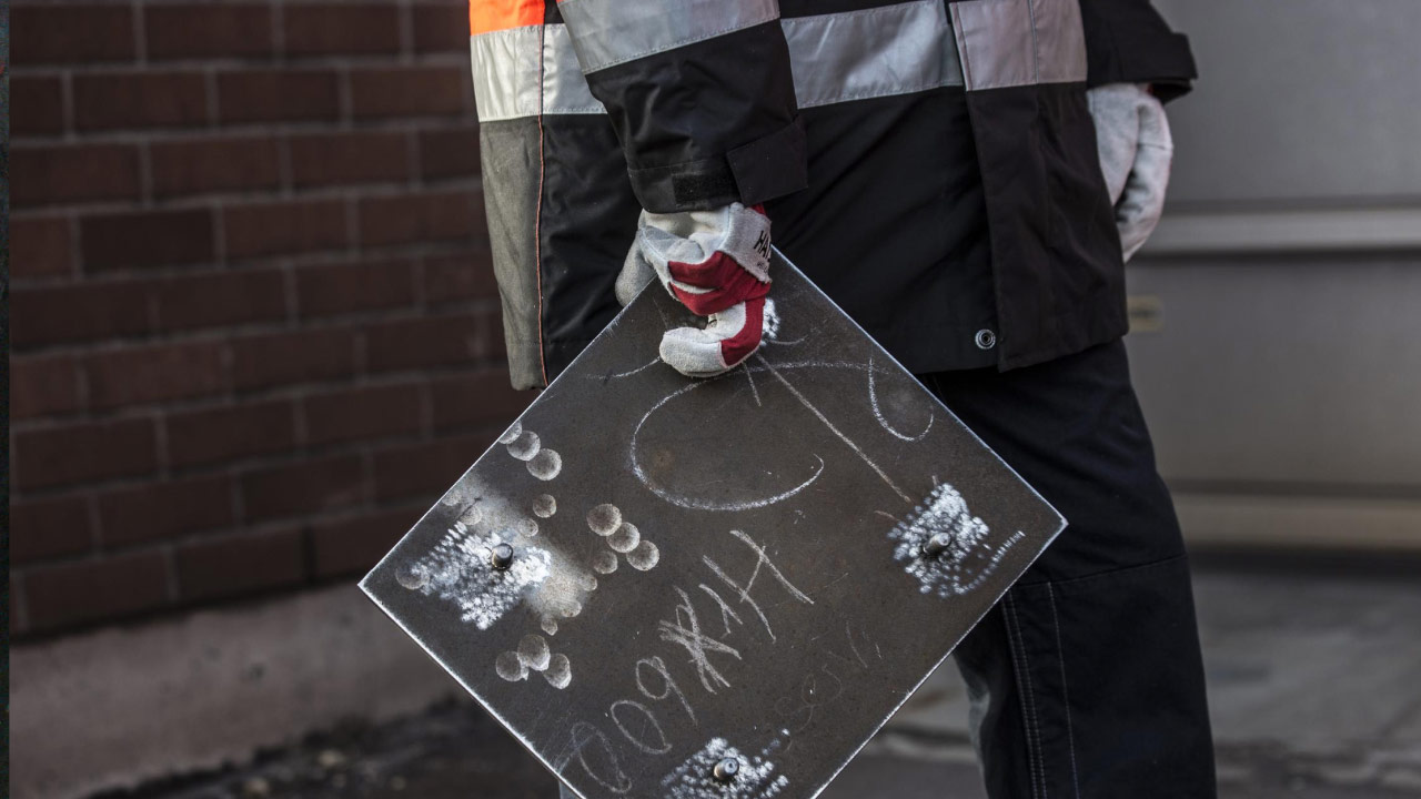 A worker’s hand holding a stud-welded liner plate of extra-hard Hardox 600 plate.